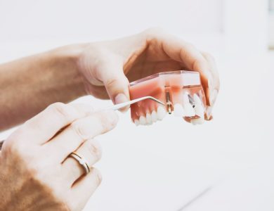 person wearing silver-colored ring while holding denture