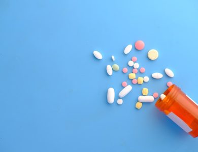colorful pills spilling from orange bottle
