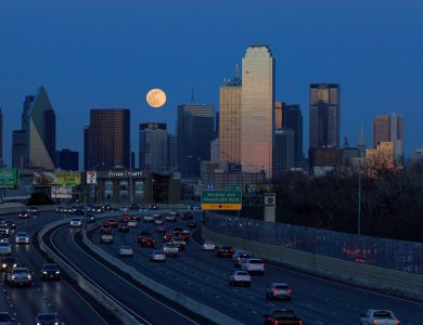 A city skyline with a full moon in the sky