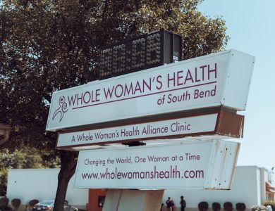 a sign with a tree in the background