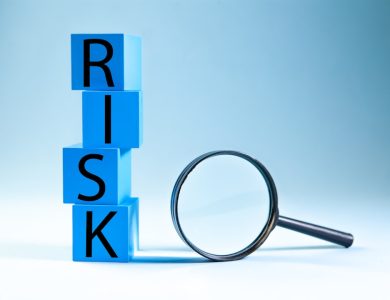 Blue blocks spelling risk next to a magnifying glass.