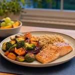 A weeknight dinner plate with salmon, brown rice, roasted vegetables, fruit and water.