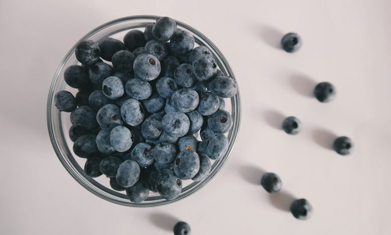 A bowl overflowing with fresh blueberries on a counter.